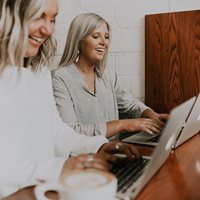 To Smilende Kvinder Siddder Ved Deres Computere