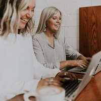 To Smilende Kvinder Siddder Ved Deres Computere