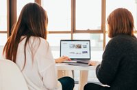 To kvinder sidder sammen foran computerskærm