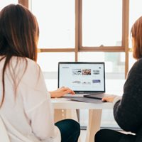 To kvinder sidder sammen foran computerskærm