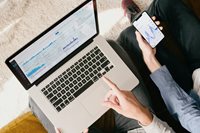 To mennesker kigger på data på en bærbar computer og en mobiltelefon