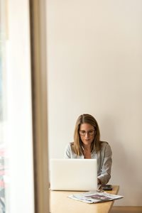 Kvinde med høretelefoner arbejder ved bærbar computer